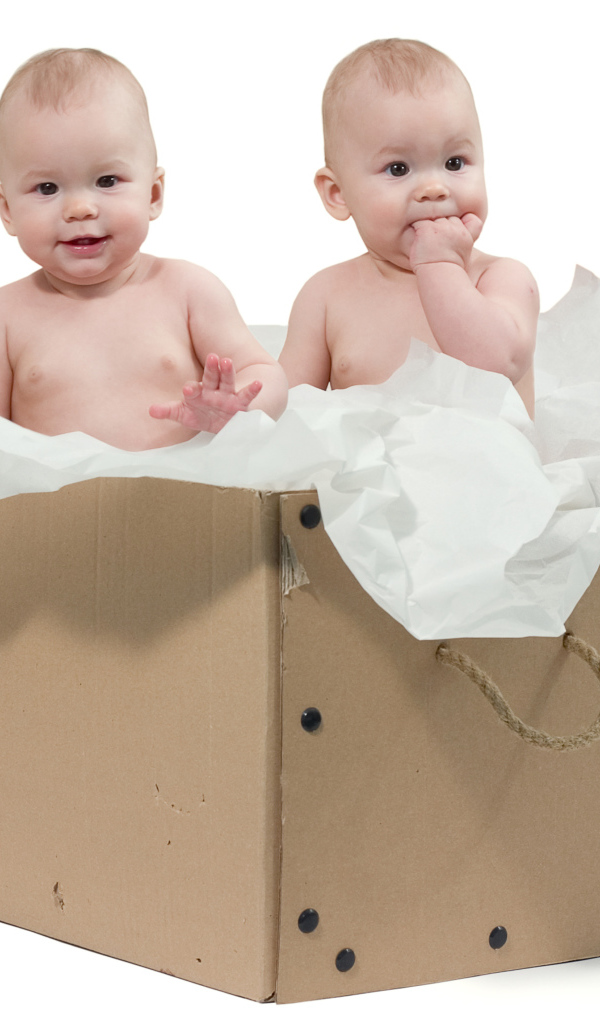 Маленькие дети сидят в картонной коробке с бумагой