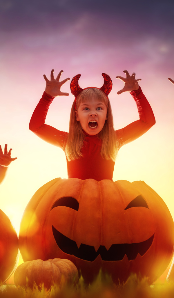 Маленькие дети в костюмах на Хэллоуин с большими тыквами