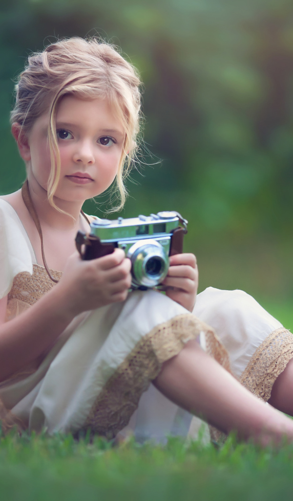 Маленькая русоволосая девочка с фотоаппаратом в руках