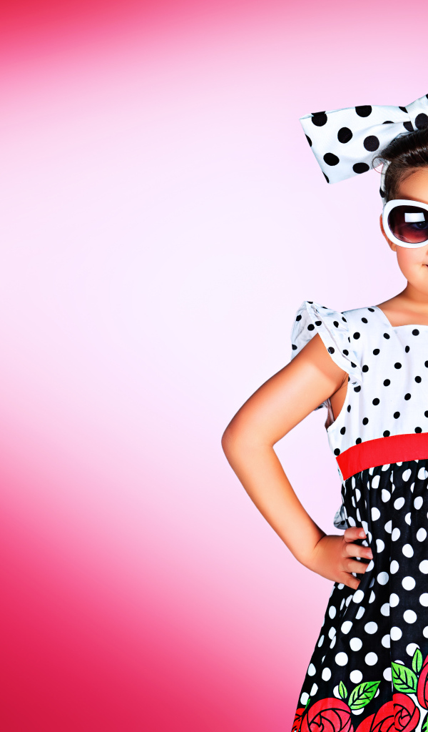 Маленькая девочка в красивом платье в горох на розовом фоне