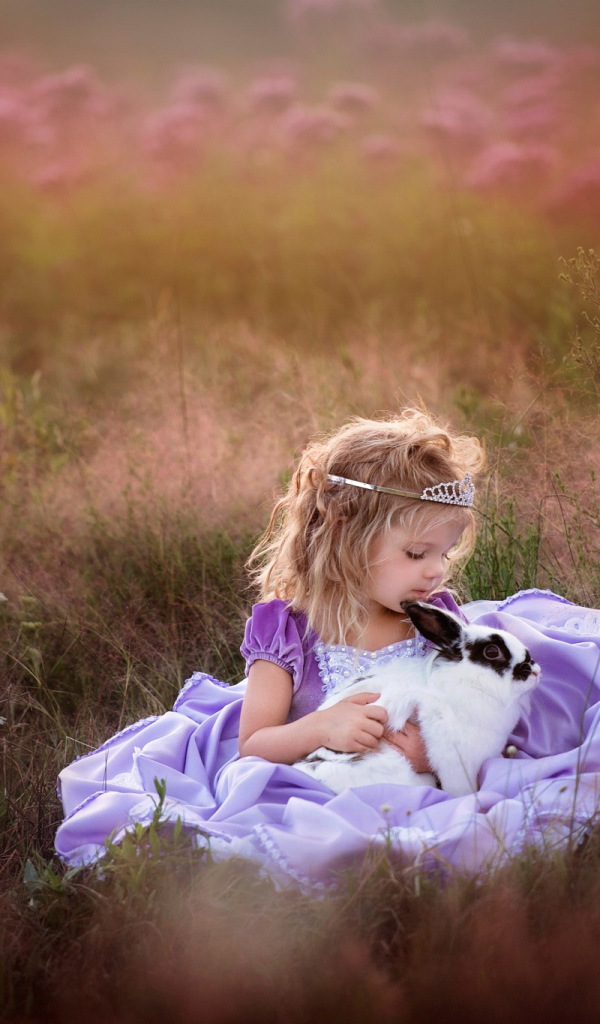 Маленькая девочка в красивом платье с кроликом в руках