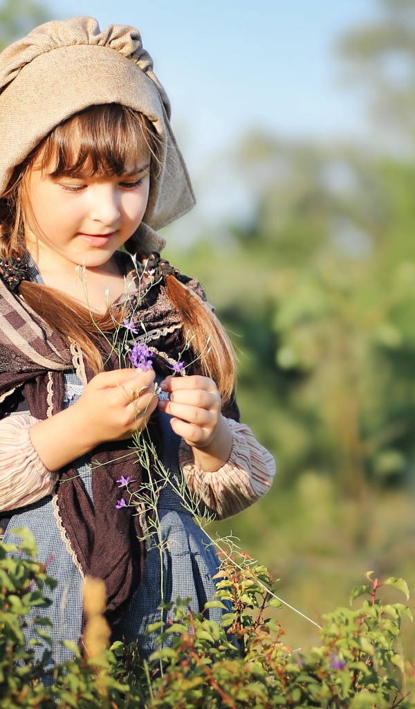 Маленькая девочка в костюме собирает травы