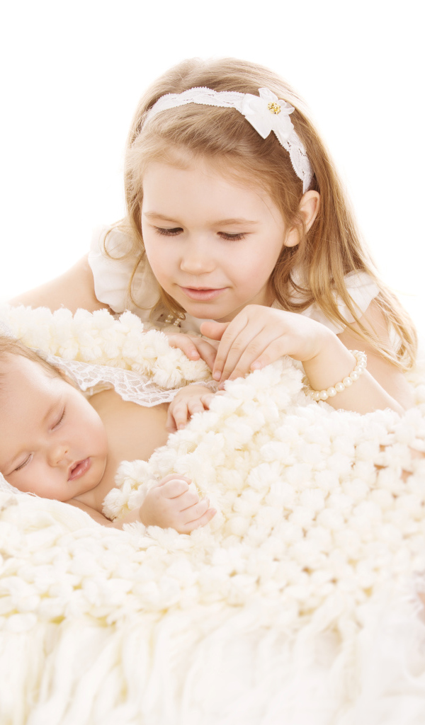 Маленькая девочка в белом со спящим младенцем на белом фоне