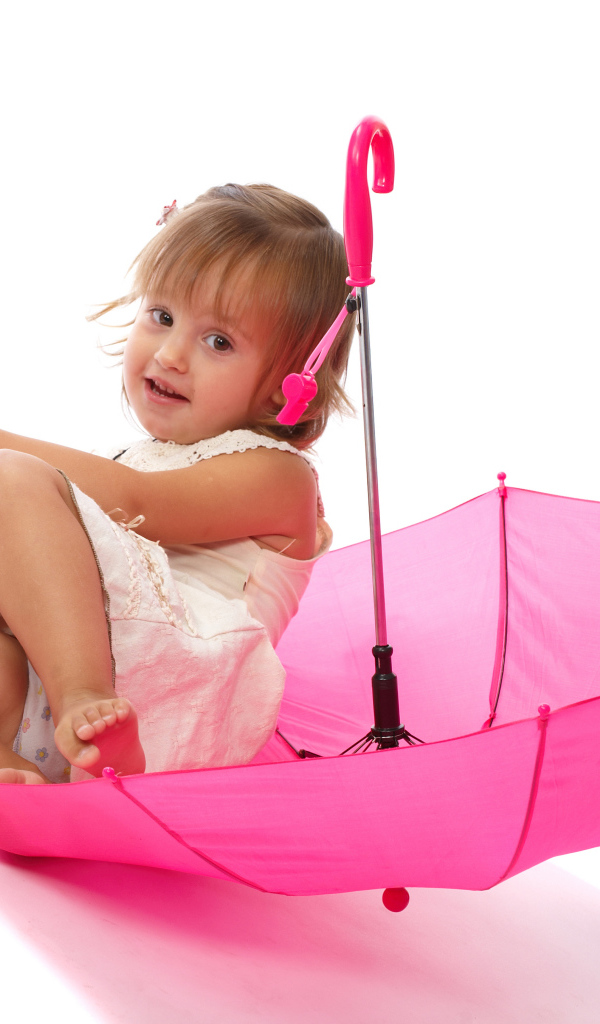 Маленькая девочка сидит в розовом зонте на белом фоне