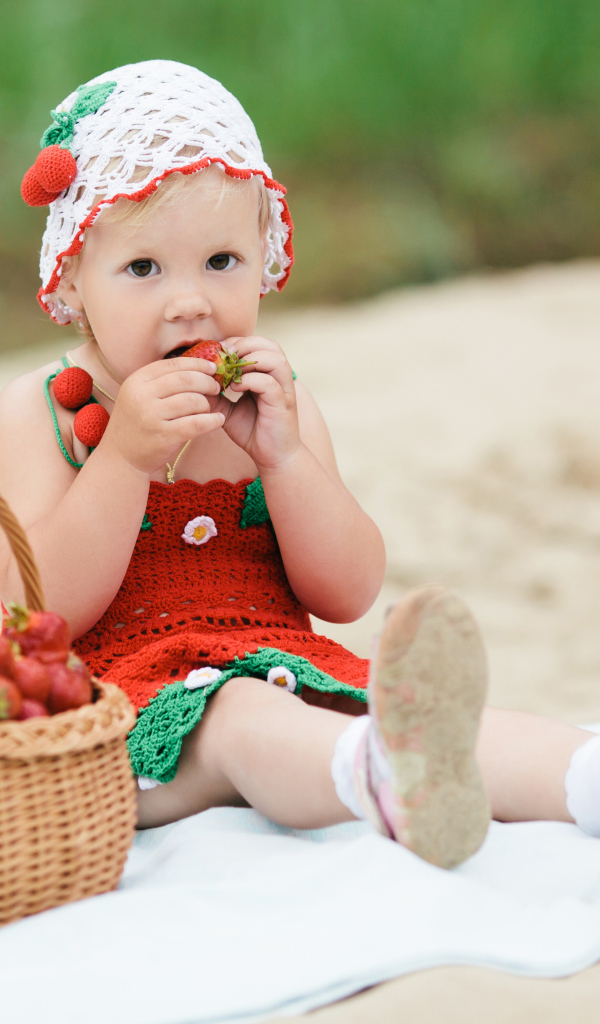 Маленькая девочка сидит с корзиной спелой клубники