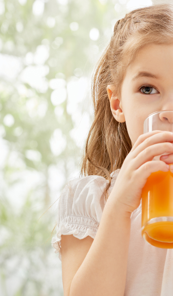 Маленькая девочка со стаканом сока в руках