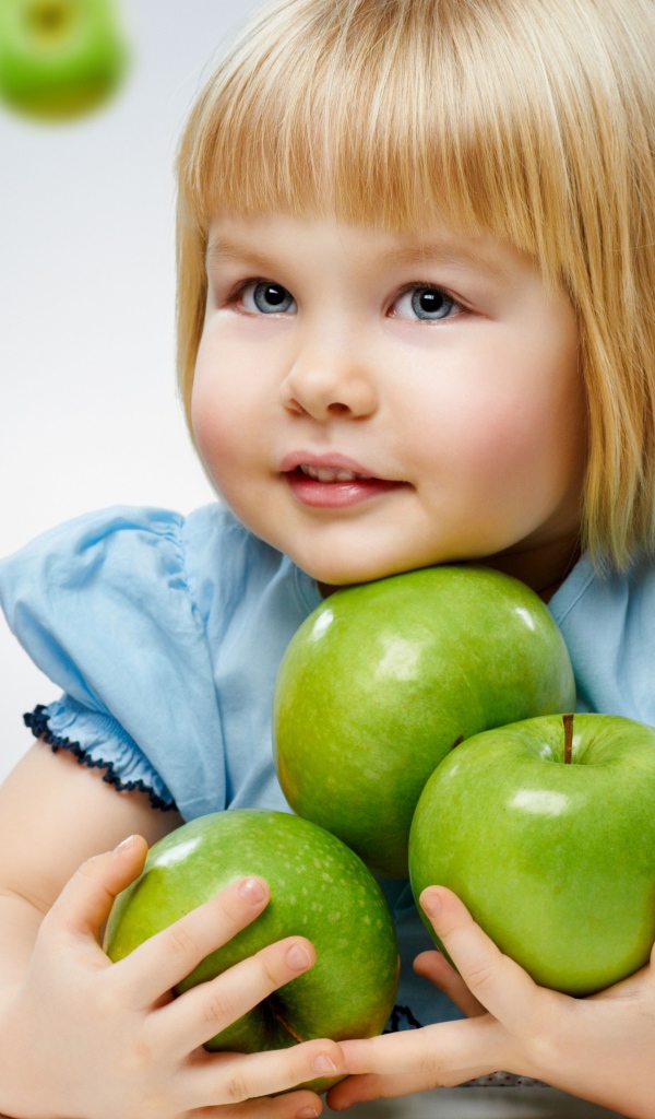 Маленькая девочка с зелеными яблоками в руках