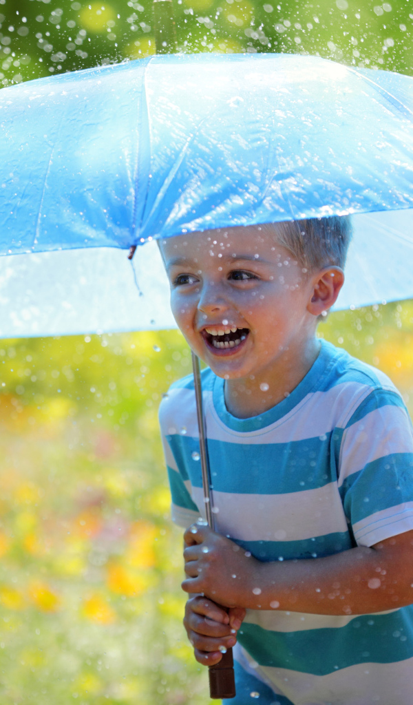 Маленький улыбающийся мальчик с голубым зонтом под дождем