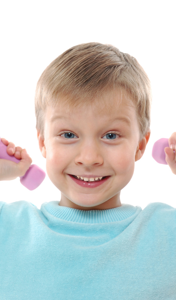 Маленький улыбающийся мальчик с гантелями на белом фоне