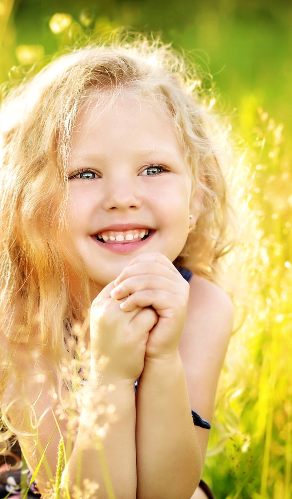 Маленькая улыбающаяся девочка в лучах солнца