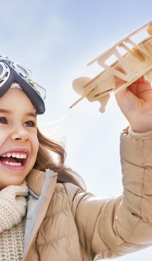 Маленькая улыбающаяся девочка с самолетом в руках 