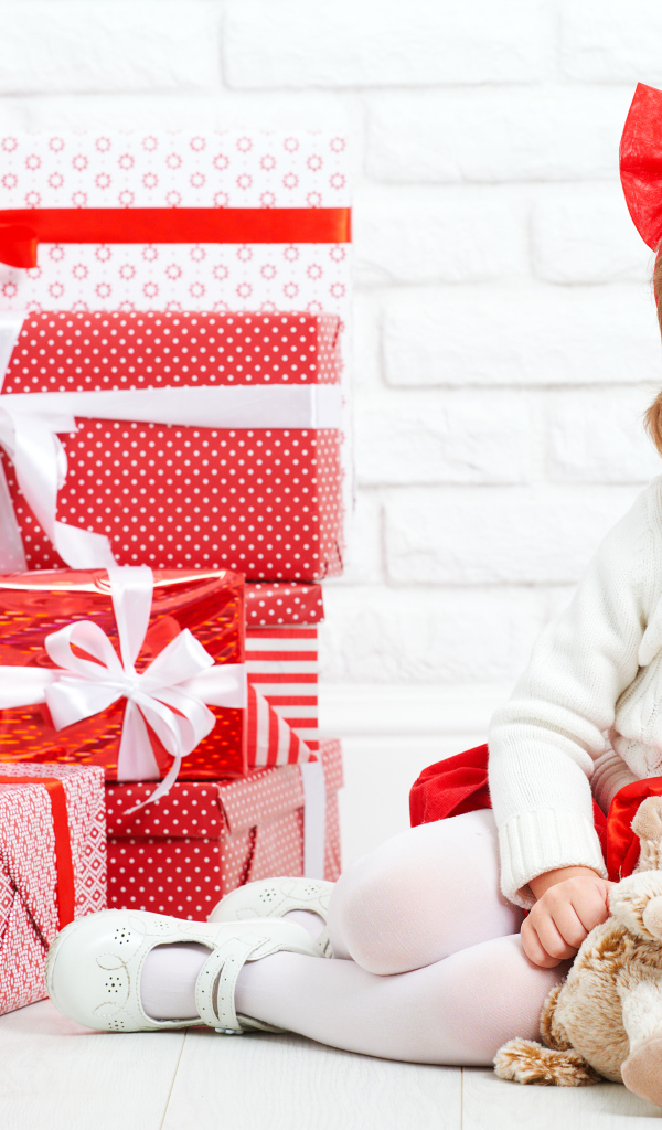 Маленькая улыбающаяся девочка с подарками на новый год