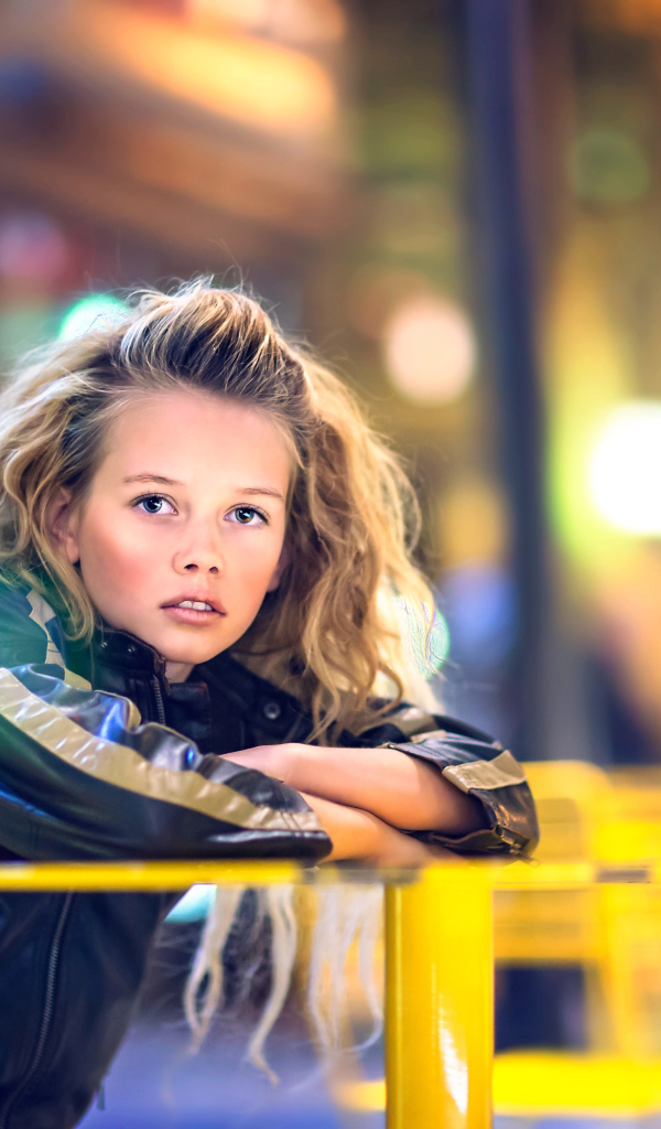 Длинноволосая девочка сидит на карусели