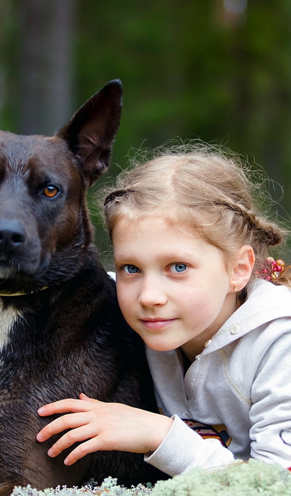 Милая голубоглазая девочка с большой черной собакой