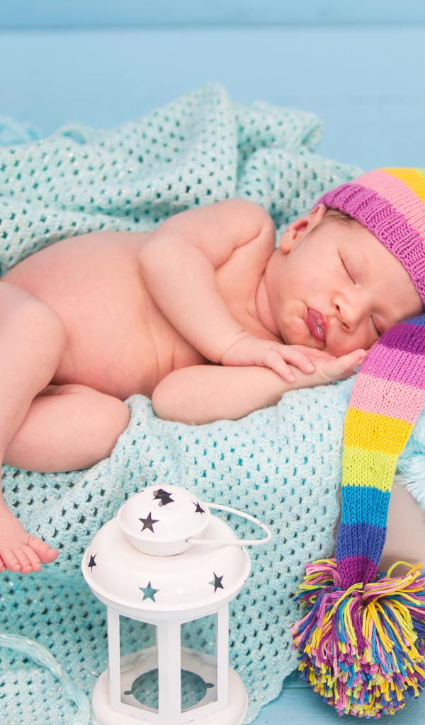 Спящий грудной ребенок в большой вязаной шапке