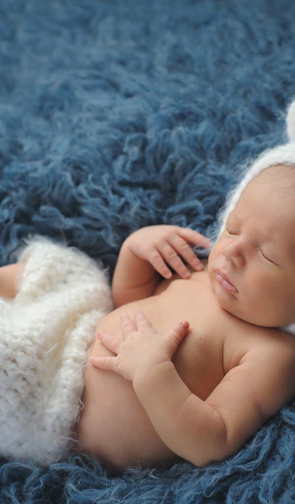 Спящий грудной ребенок в белом костюме медвежонка