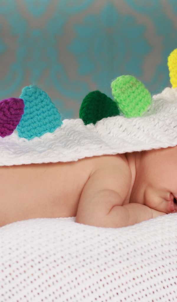 Спящий младенец в белой вязаной накидке