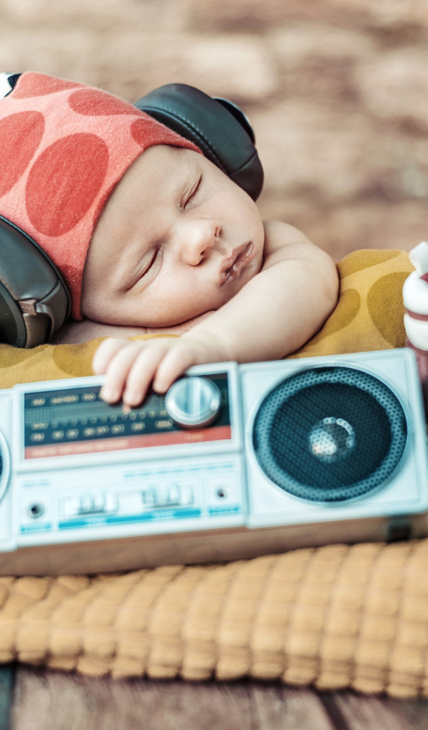Спящий младенец в наушниках и с игрушечным магнитофоном