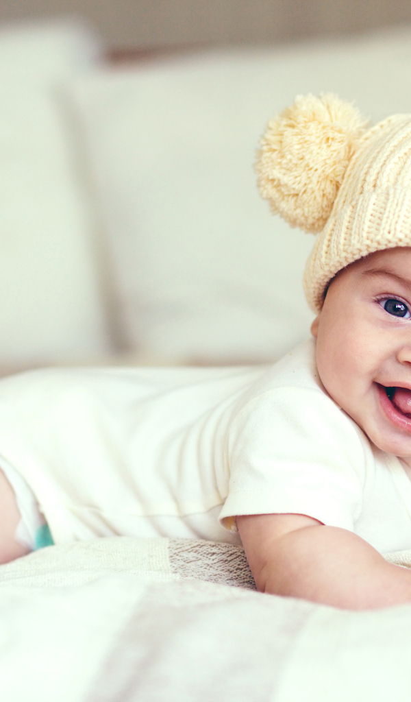 Улыбающийся грудной ребенок в забавной вязаной шапке