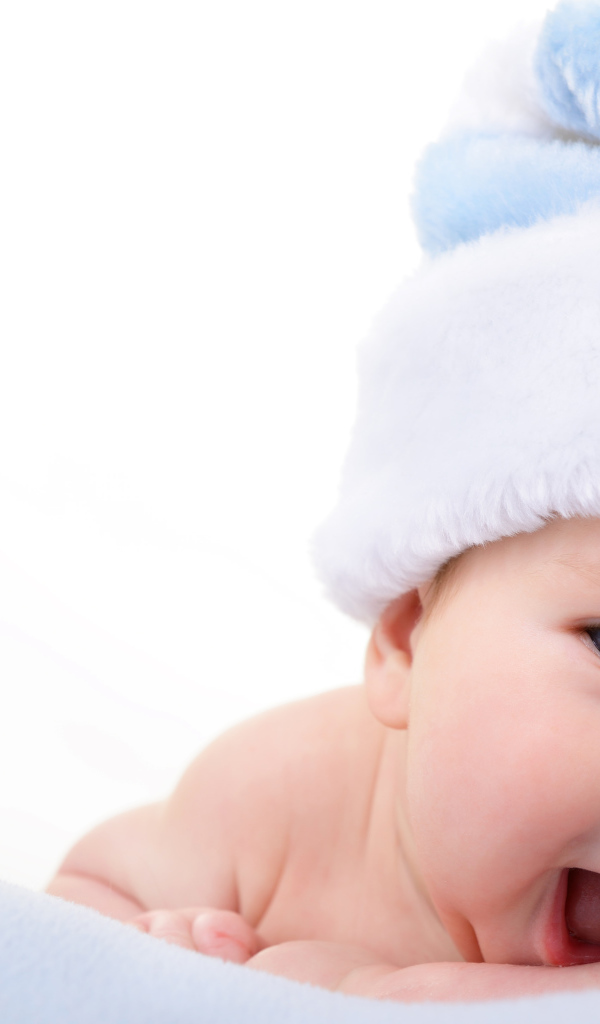 Улыбающийся грудной ребенок в голубой новогодней шапке