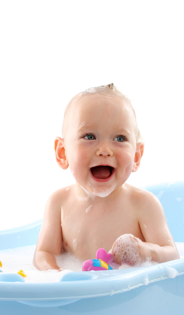 Улыбающийся грудной ребенок сидит в синей ванночке на белом фоне