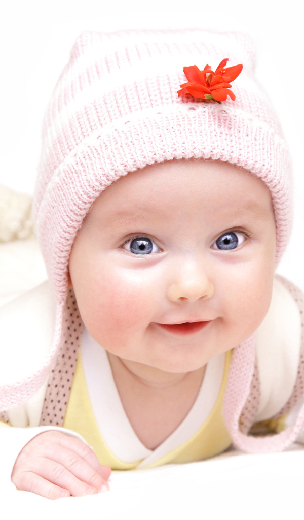 Улыбающийся голубоглазый малыш в розовой шапке
