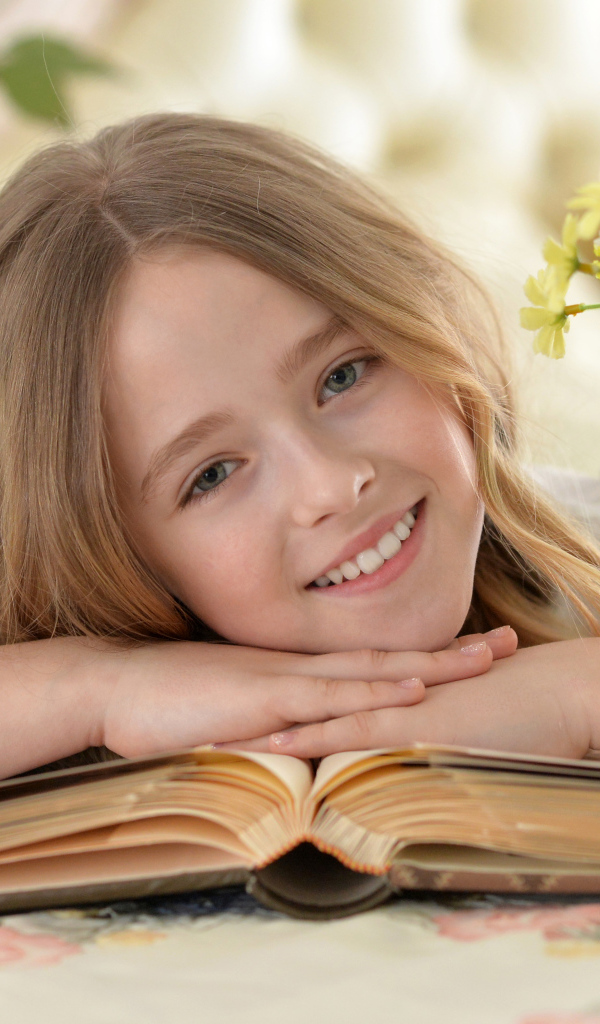Улыбающаяся русоволосая девочка с книгой