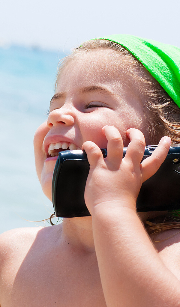 Улыбающаяся девочка в зеленом платке разговаривает по телефону