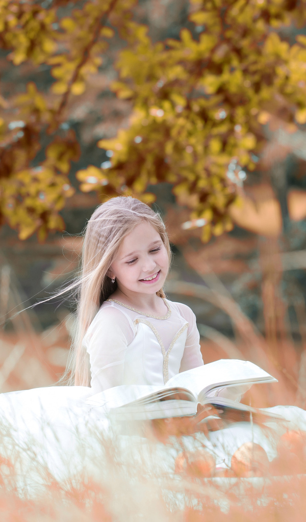 Улыбающаяся девочка в белом платье читает книгу
