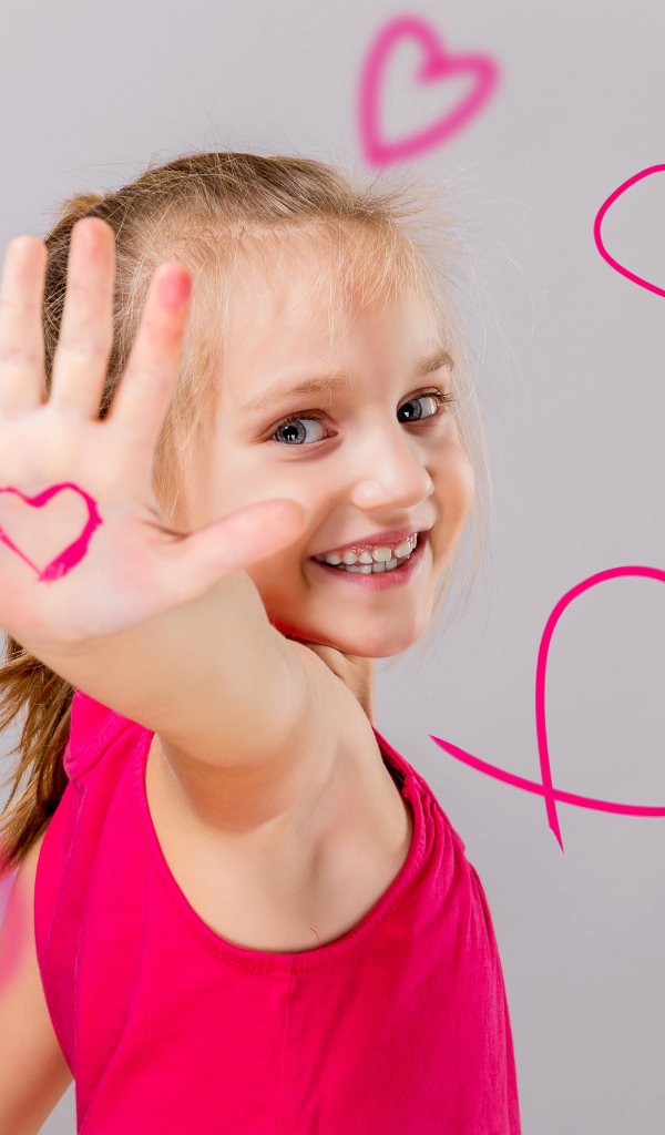 Улыбающаяся девочка с нарисованными сердечками на сером фоне