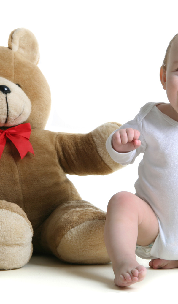 Улыбающийся малыш с большим плюшевым медведем на белом фоне