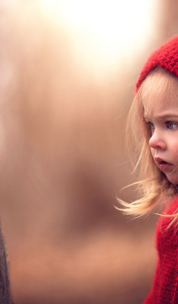 Удивленная девочка в красном капюшоне смотрит на лягушку