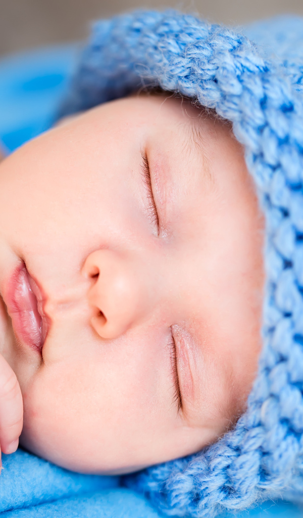 Милый спящий младенец с синей вязаной шапке