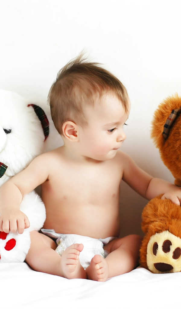 Младенец сидит с двумя большими плюшевыми медведями