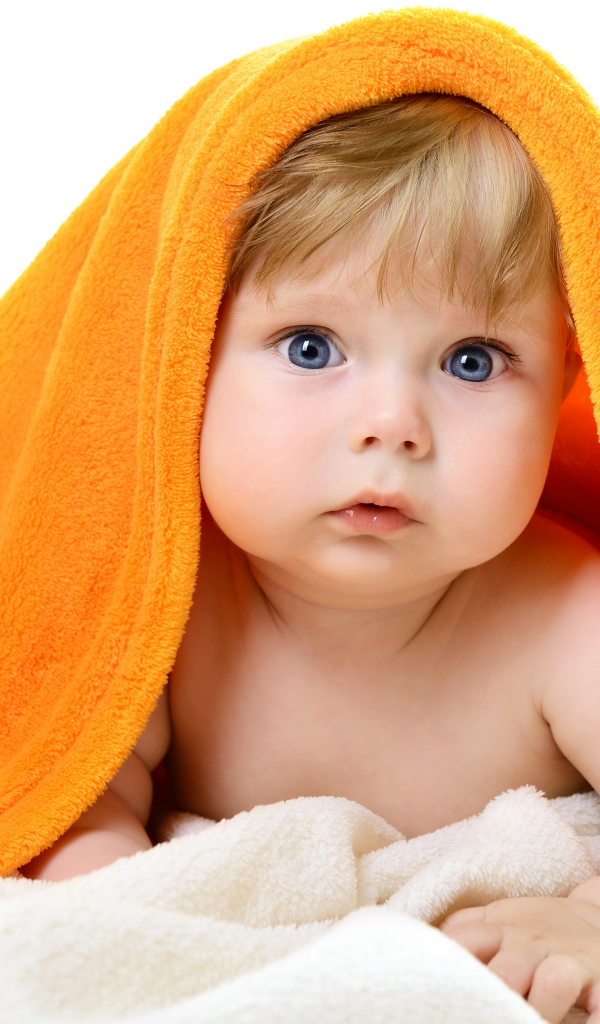 Голубоглазый малыш лежит под оранжевым покрывалом