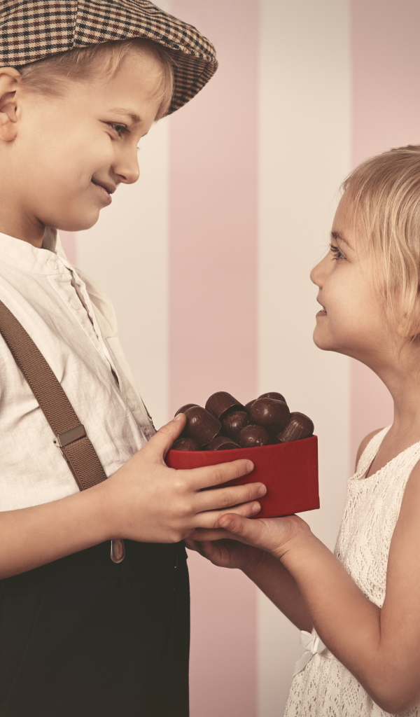 Мальчик дарит девочке коробку шоколадных конфет