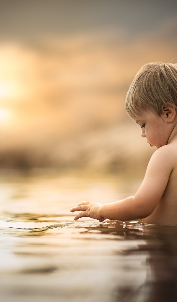 Маленький мальчик купается в воде 