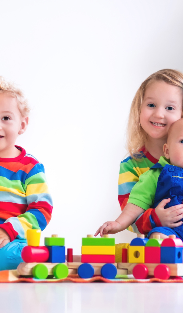 Три ребенка играют с игрушечным поездом