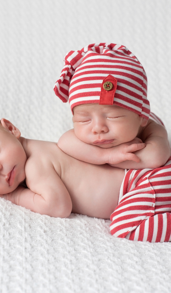 Два милых спящих младенца в полосатых костюмах