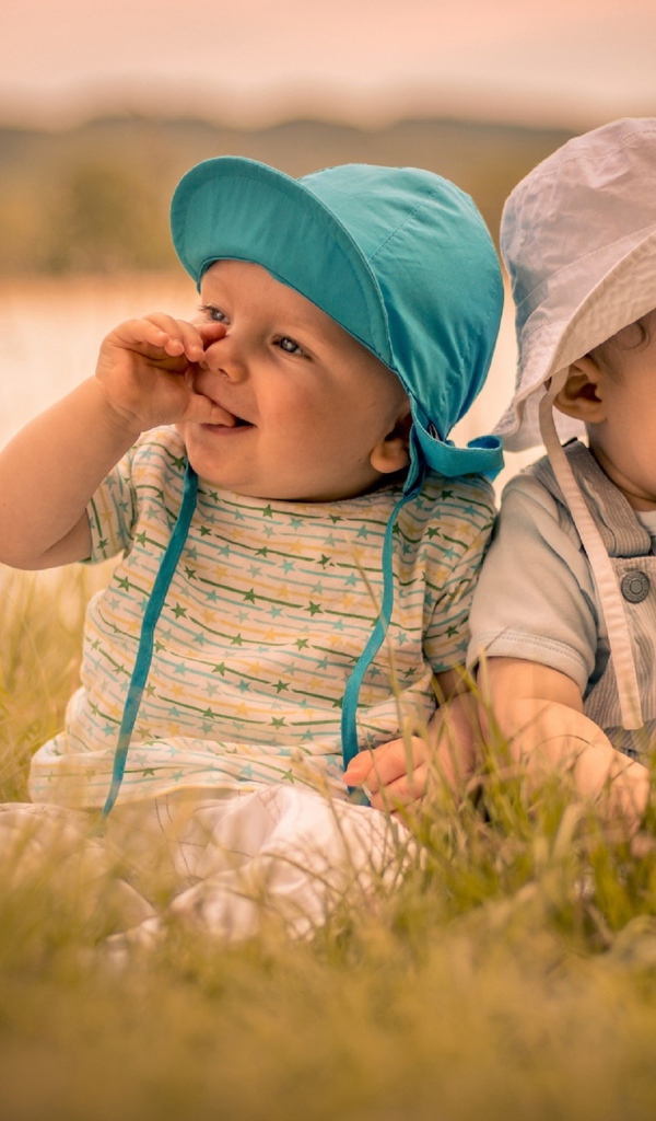 Два милых малыша в зеленой траве летом 