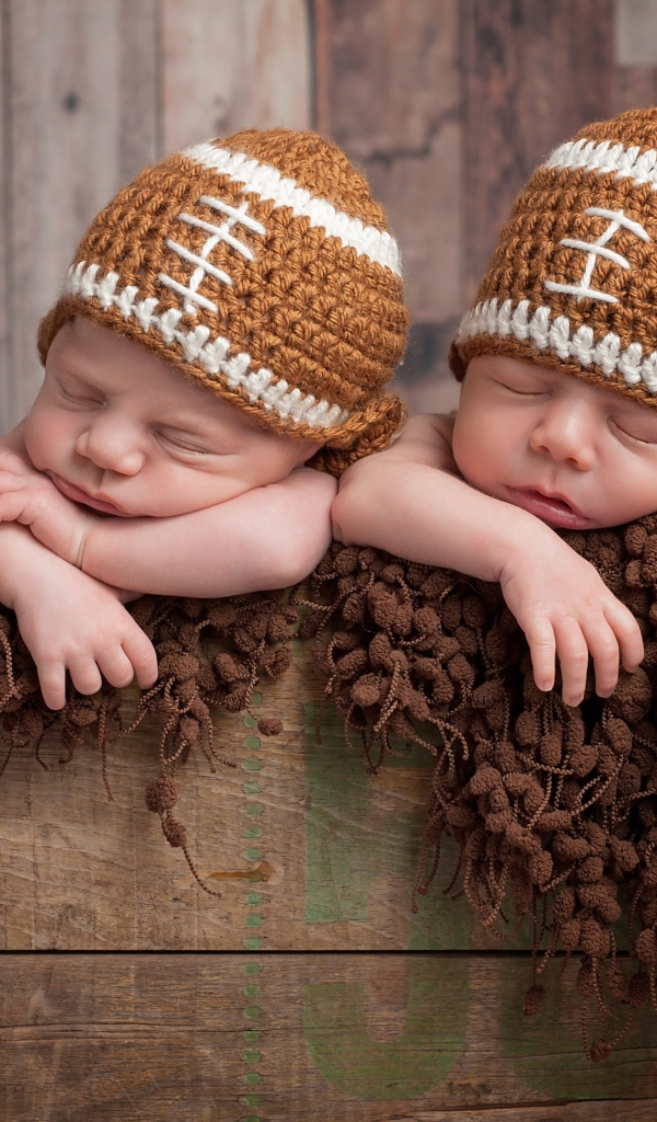 Два милых спящих малыша в забавных вязаных шапках