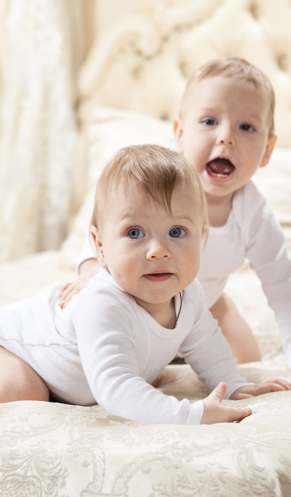 Два забавных младенца лежат на кровати