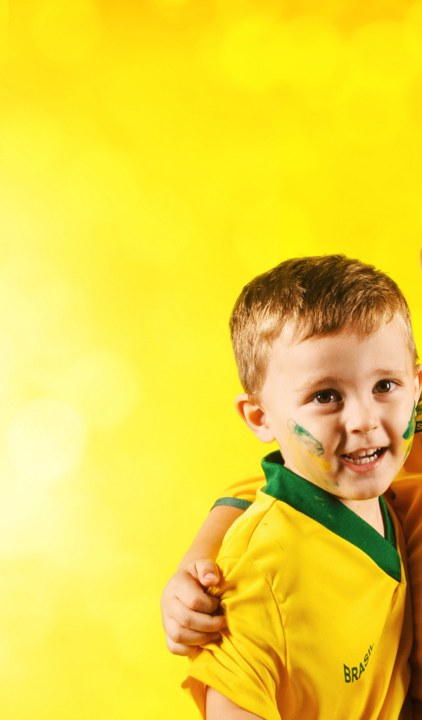 Два маленьких мальчика в спортивной форме на желтом фоне