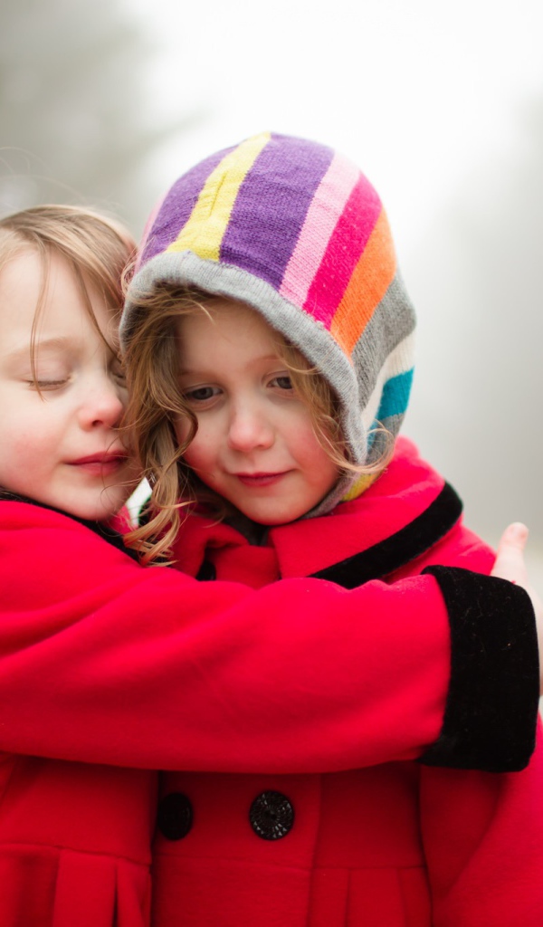 Две маленькие девочки обнимают друг друга 