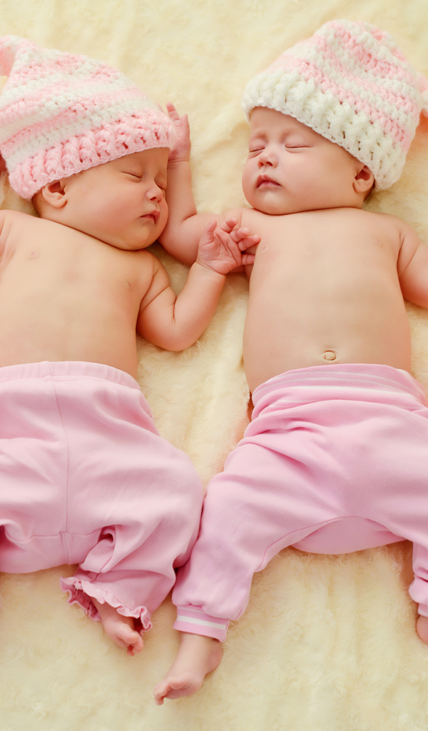Два спящих грудных ребенка в розовых костюмах