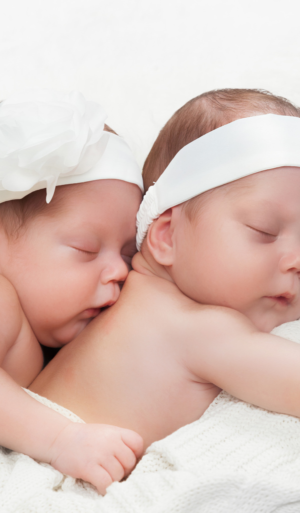 Два спящих младенца с большими белыми цветами на голове