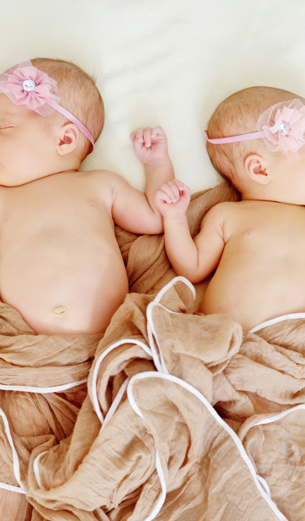 Два спящих младенца с розовыми цветами на голове