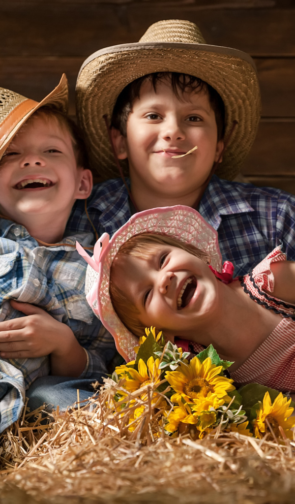 Два улыбающихся мальчика и девочка в соломенных  шляпах