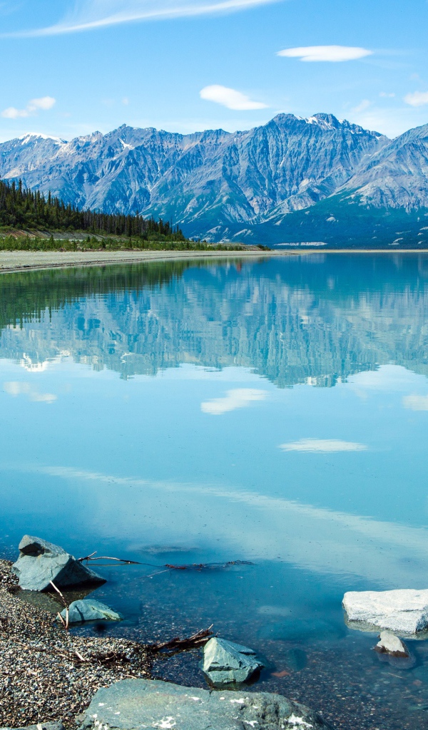 Горы отражаются в голубой воде озера Клуэйн, Национальный парк на территории Юкон, Канада.