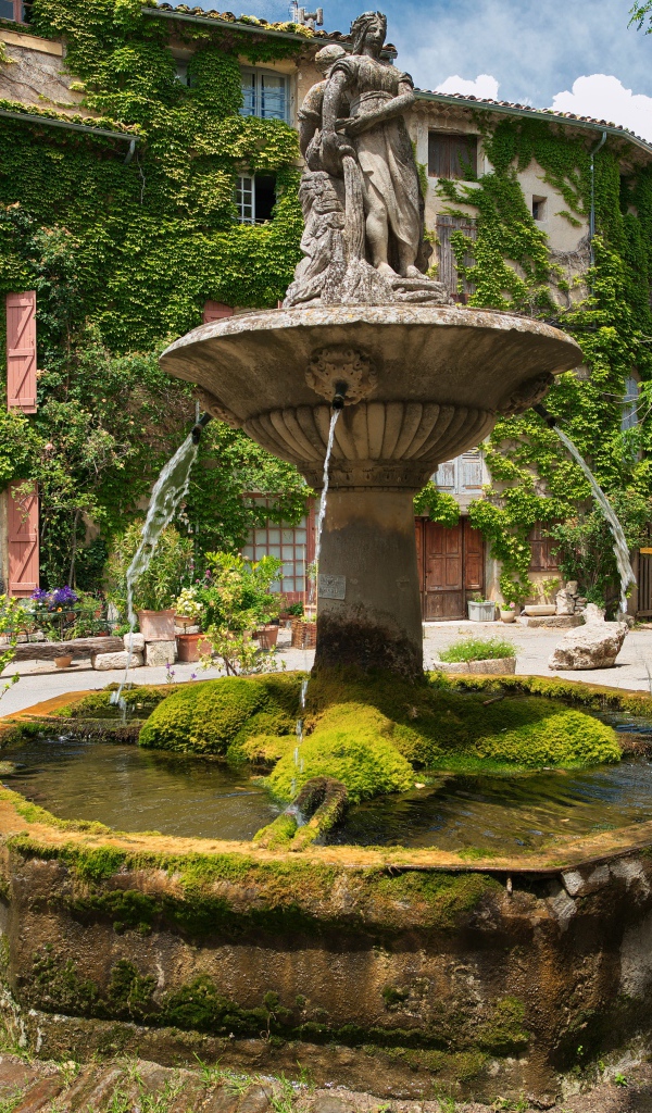 Ancient moss-covered fountain in the square of Segnon, France